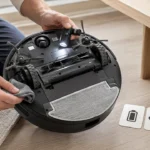 Begagnad robotdammsugare granskas undertill för borstar, hjul, sensorer och batteri